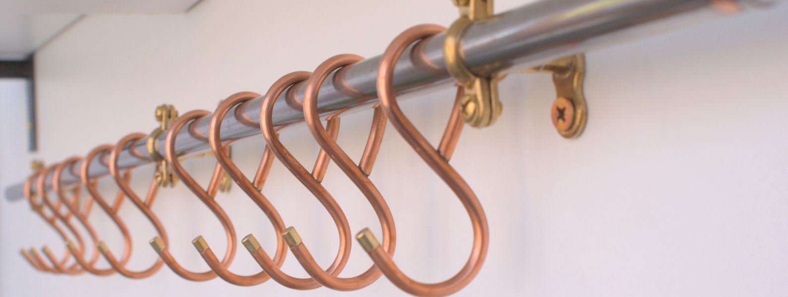 Close-up of French-style copper hooks on black steel rack