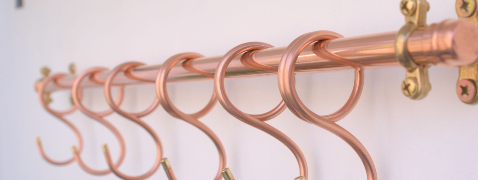 Close-up of modern 24-inch copper pot hooks, wall-mounted