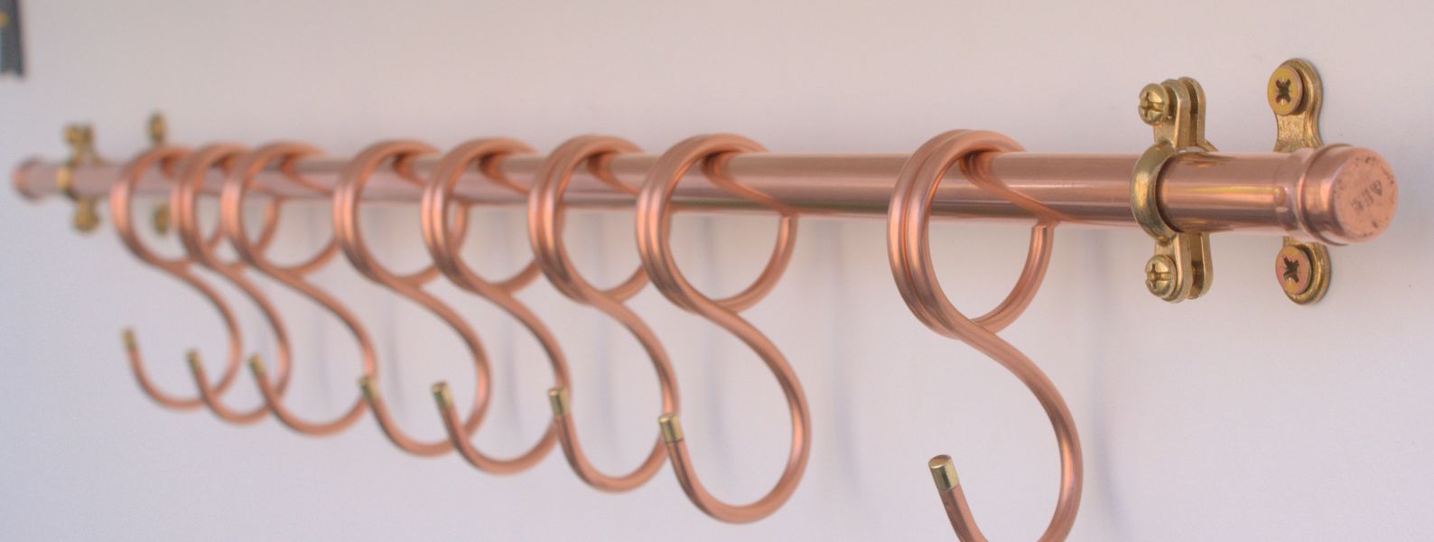 Large modern copper pot rack in handcrafted kitchen setting