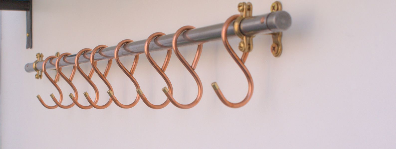 Hand-forged copper hooks on black steel skillet rail, 31-inch